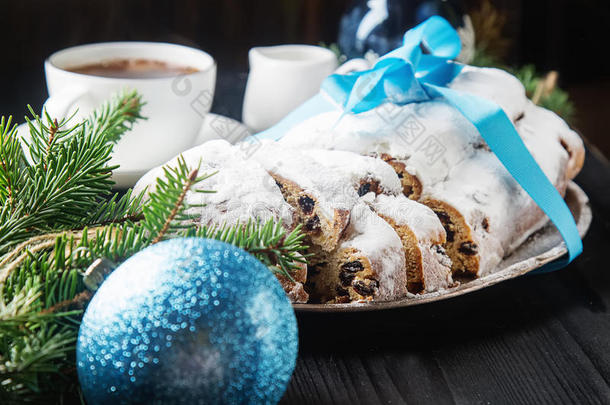 圣诞斯托伦放在一个银色托盘上，里面有一杯白咖啡、一个毛皮树枝圣诞玩具、桑塔克劳和蓝色气球
