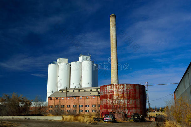 废弃的工厂，有储罐，烟囱，和一个农业粮食电梯筒仓的背景