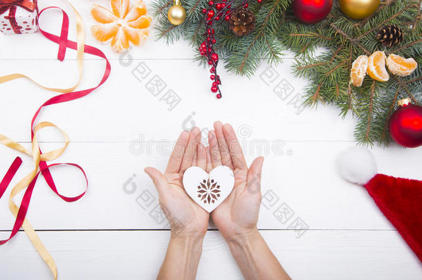 双手捧着白色的心在圣诞装饰背景上