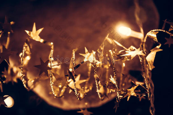 金色闪亮的星星与闪闪发光的圣诞灯在圣诞夜的金色作为圣诞背景