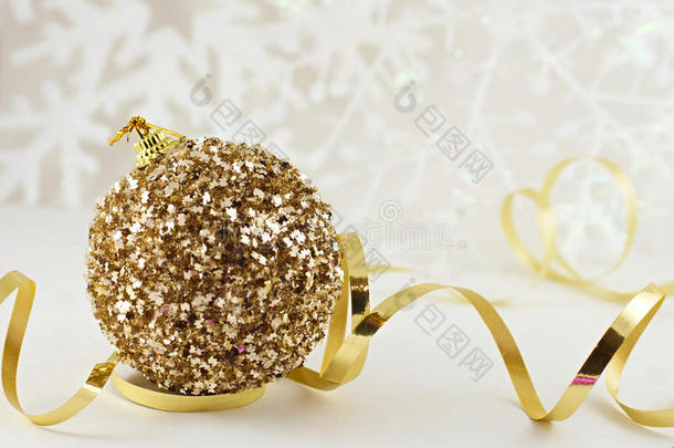 金色圣诞球，带丝带，以温暖的色调软化轻雪花背景。