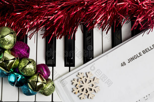 圣诞音乐概念。钢琴上的印刷音乐，铃铛叮当作响，雪花飘落，飘飘欲滴