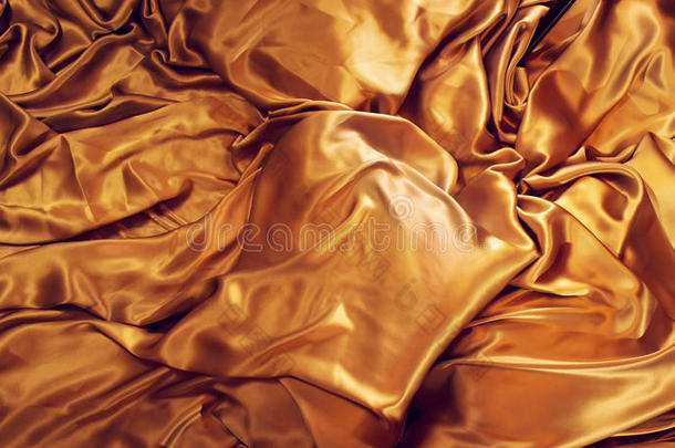 金色的丝绸背景。 缎子织物背景