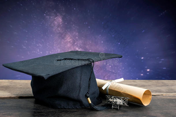 毕业帽，帽子，学位纸在木桌上，银河