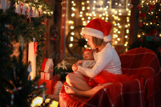 女孩戴着圣诞帽，最<strong>喜</strong>欢的玩具<strong>娃娃</strong>在壁炉旁，克里斯姆