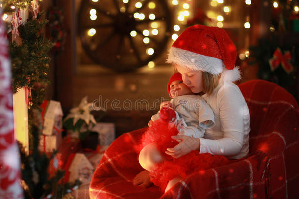 女孩戴着圣诞帽，最喜欢的玩具娃娃在壁炉旁，克里斯姆