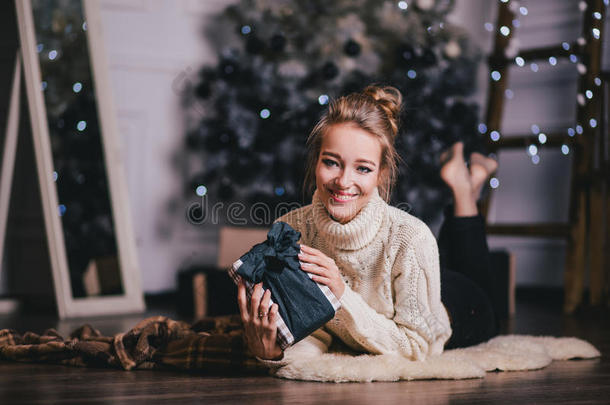 美丽的年轻女人在圣诞树<strong>下摆</strong>姿势