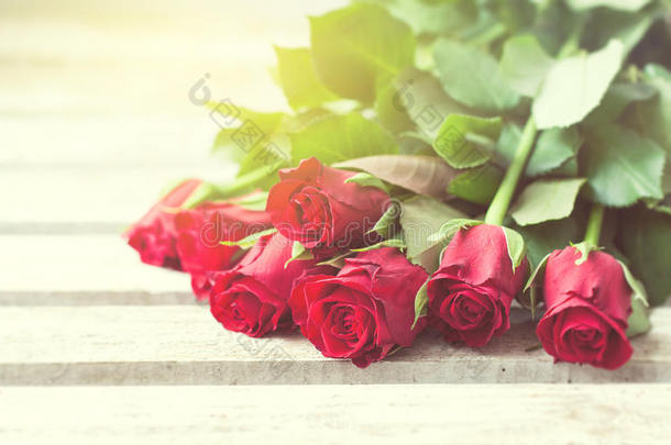 美丽的红色玫瑰在木制背景上，有美丽的光线