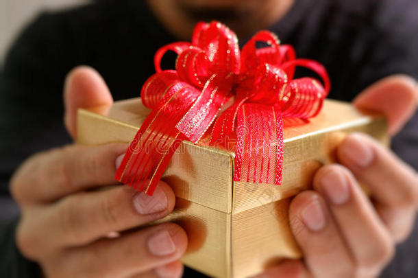 送礼，男人用手拿着礼品盒，表示送礼。模糊的背景，复古的效果