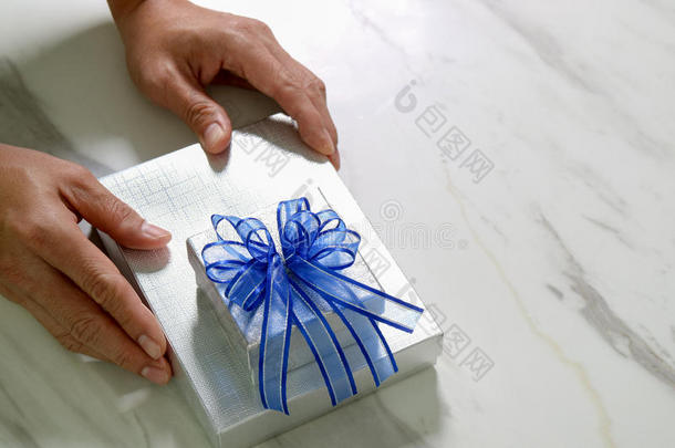 送礼，男人用手拿着礼品盒，以表示送礼。模糊的背景