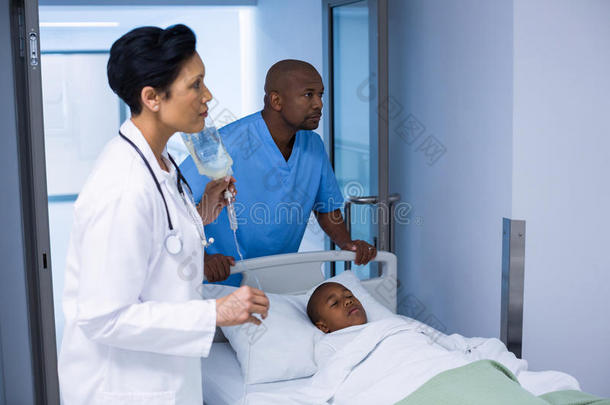 医生调整静脉滴注，而病人躺在床上