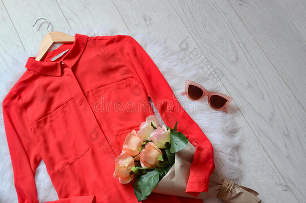 时尚概念。 红色衬衫，在浅色背景上有一束玫瑰和粉红色的眼镜。