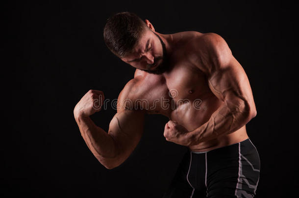 一个力量健身者`手的特写。 强壮英俊的年轻健美运动员展示了他的肌肉和二头肌