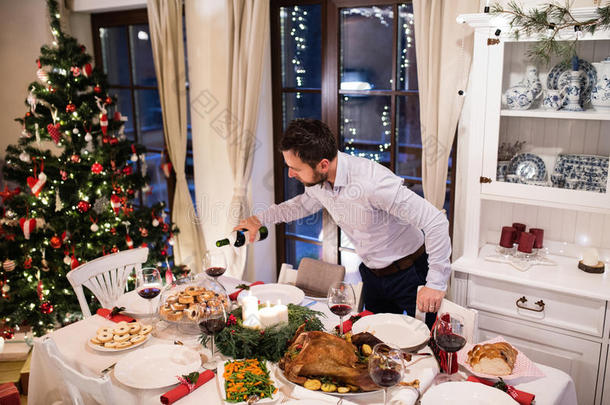 圣诞大餐摆在桌子上。 男人把酒倒进眼镜里。
