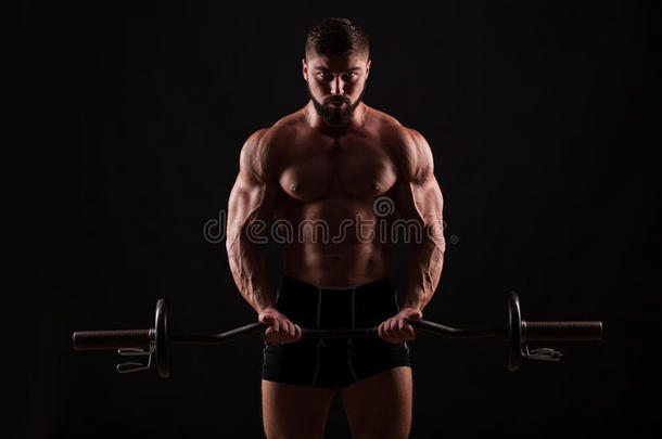 一个肌肉男在健身房用杠铃锻炼的特写照片。