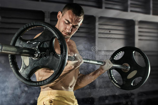 特写照片的英俊健美男子准备做运动与杠铃在健身房，保持杠铃板在手