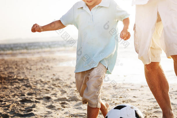 父子玩足球海滩夏天的概念