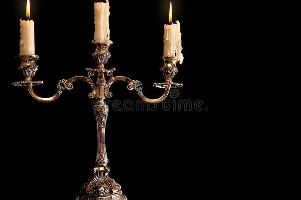 烧旧蜡烛<strong>古铜</strong>银烛台。孤立的黑色背景。