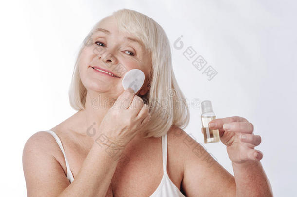 高兴的老年妇女有她的日常皮肤护理常规