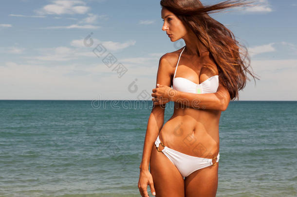 迷人的女孩在海滩上享受炎热的夏日。