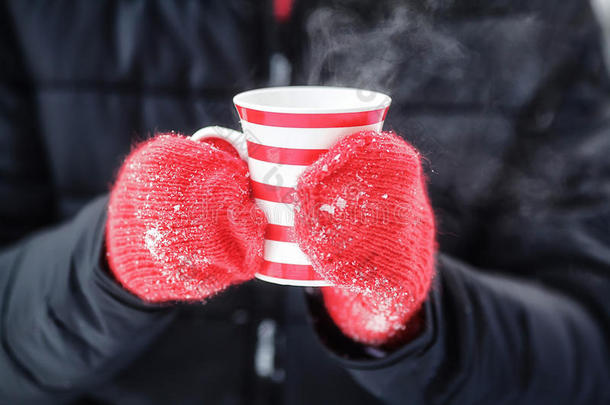 双手戴着红色手套，拿着热气腾腾的冬天杯子