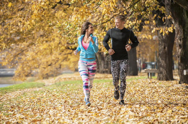 美丽的年轻夫妇在公园里一起跑步。