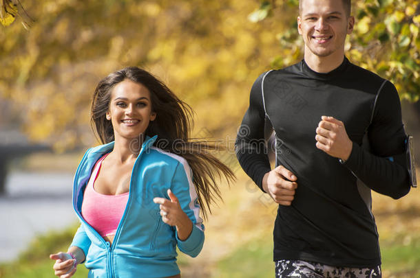 美丽的年轻夫妇在公园里一起跑步。