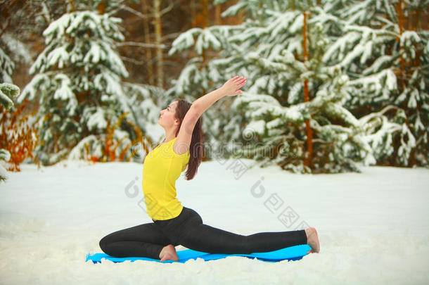 美丽的女人在雪地里户外做瑜伽