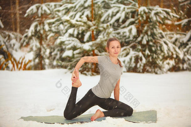 美丽的女人在雪地里户外做瑜伽