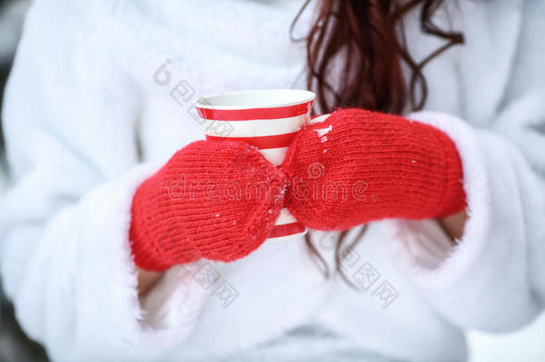 双手戴着红色手套，拿着热气腾腾的冬天杯子