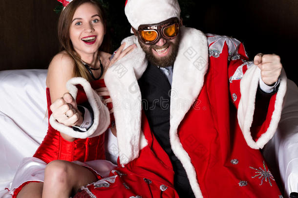 残忍的圣诞老人和穿着狂欢节服装的女护士，像开车一样在沙发上开车
