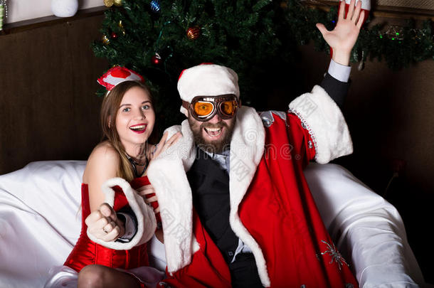 残忍的圣诞老人和穿着狂欢节服装的女护士，像开车一样在沙发上开车