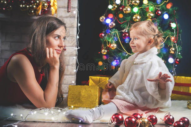 可爱的婴儿和妈妈装饰圣诞树。 红球。