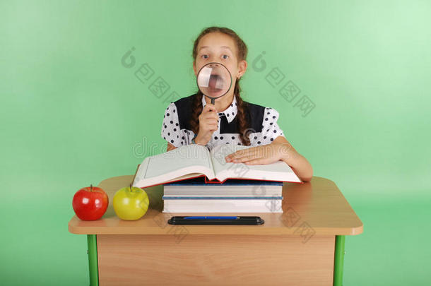 穿着校服的女孩坐在书桌前拿着放大镜