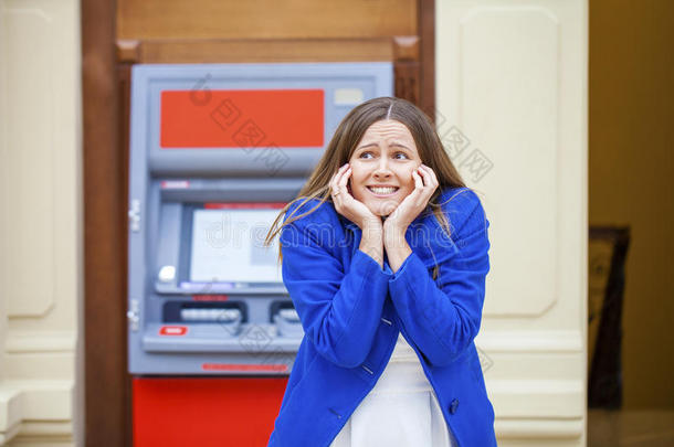 沮丧的年轻女人站在反对ATM