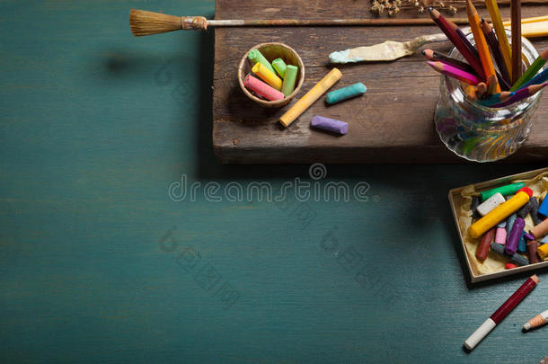 一位艺术家的桌子，上面有许多绿色<strong>木制</strong>背景上的文具<strong>物品</strong>。