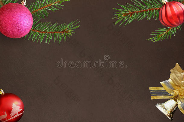 圣诞冷杉树枝，红色波浪和粉红色的球，深色背景上的铃铛装饰