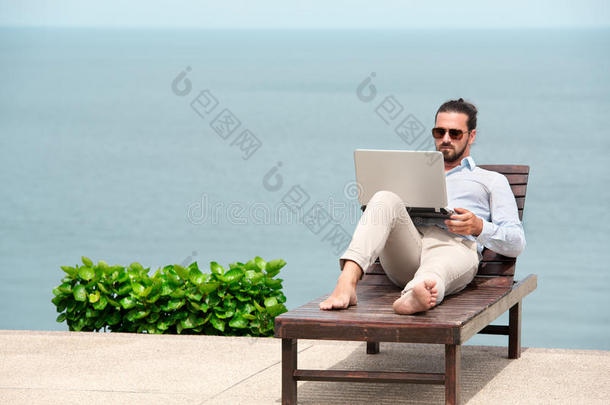 穿着西装的商人在海滩<strong>上</strong>用笔记本电脑