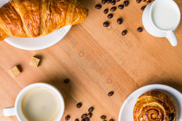 咖啡杯与牛奶罐，朱砂和牛角面包在木制背景。