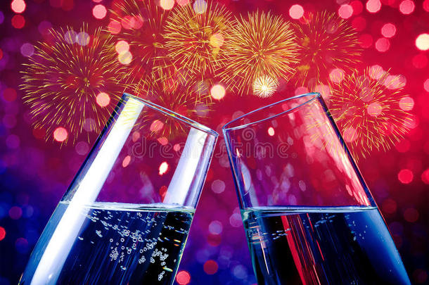 香槟长笛与金色气泡在红色和紫色的灯光Bokeh和烟花闪耀背景