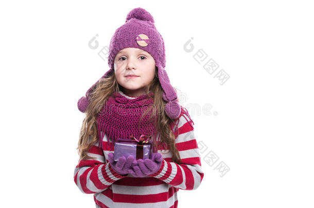可爱微笑的小女孩戴着紫色针织围巾，戴着帽子和手套，拿着白色背景上隔离的圣诞礼物。