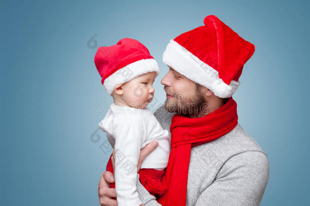 父亲带着小男孩戴着圣诞老人的帽子庆祝圣诞节