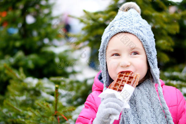 可爱的小女孩在寒冷的冬天吃温暖的华夫饼