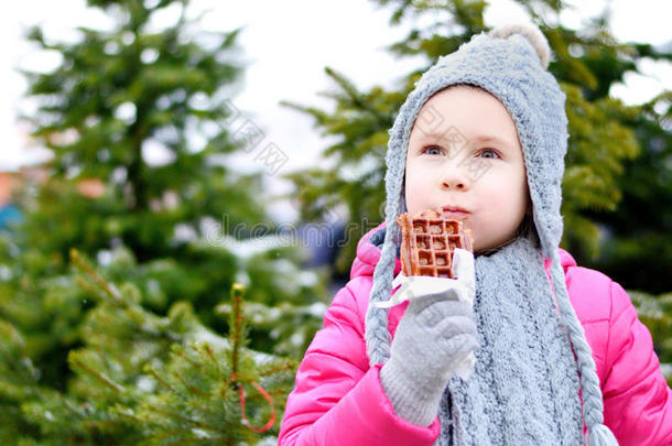 可爱的小女孩在寒冷的冬天吃温暖的华夫饼