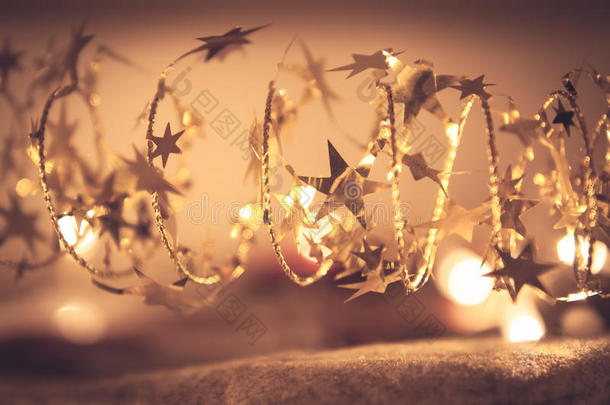 金色闪亮的星星花环与闪闪发光的圣诞灯在<strong>圣诞夜</strong>的金色作为豪华的圣诞节背景