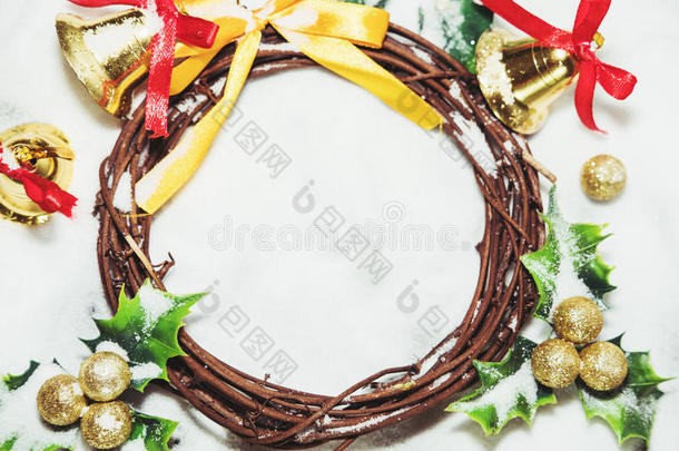 圣诞背景，花环是从藤蔓的树枝上编织出来的，上面有金色的铃铛和绿叶