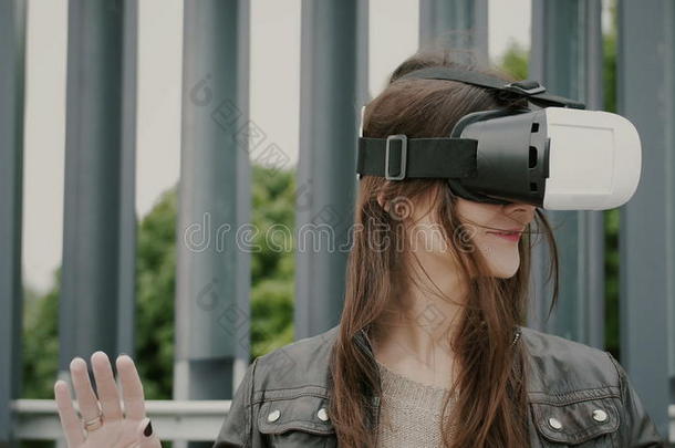 黑发女子女孩挥舞着头发，在城市空间使用虚拟现实眼镜。 4k