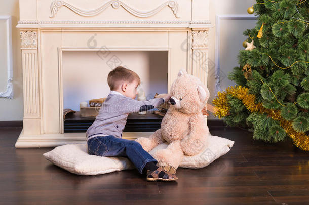 小男孩在圣诞树下玩玩具熊。