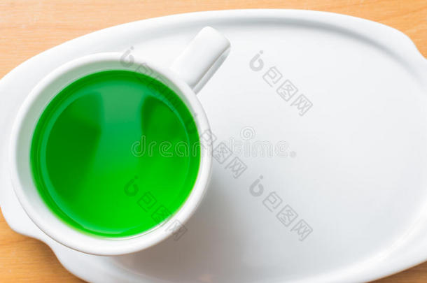 绿色蜜露在木桌上的杯子里。