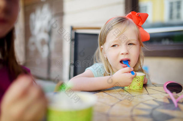 有趣的小女孩在夏天的户外咖啡馆里吃冰淇淋